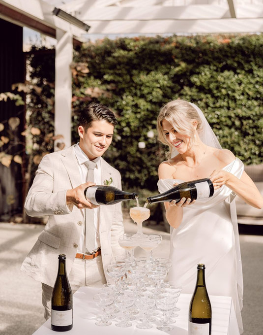 Bride and groom pouring champagne.