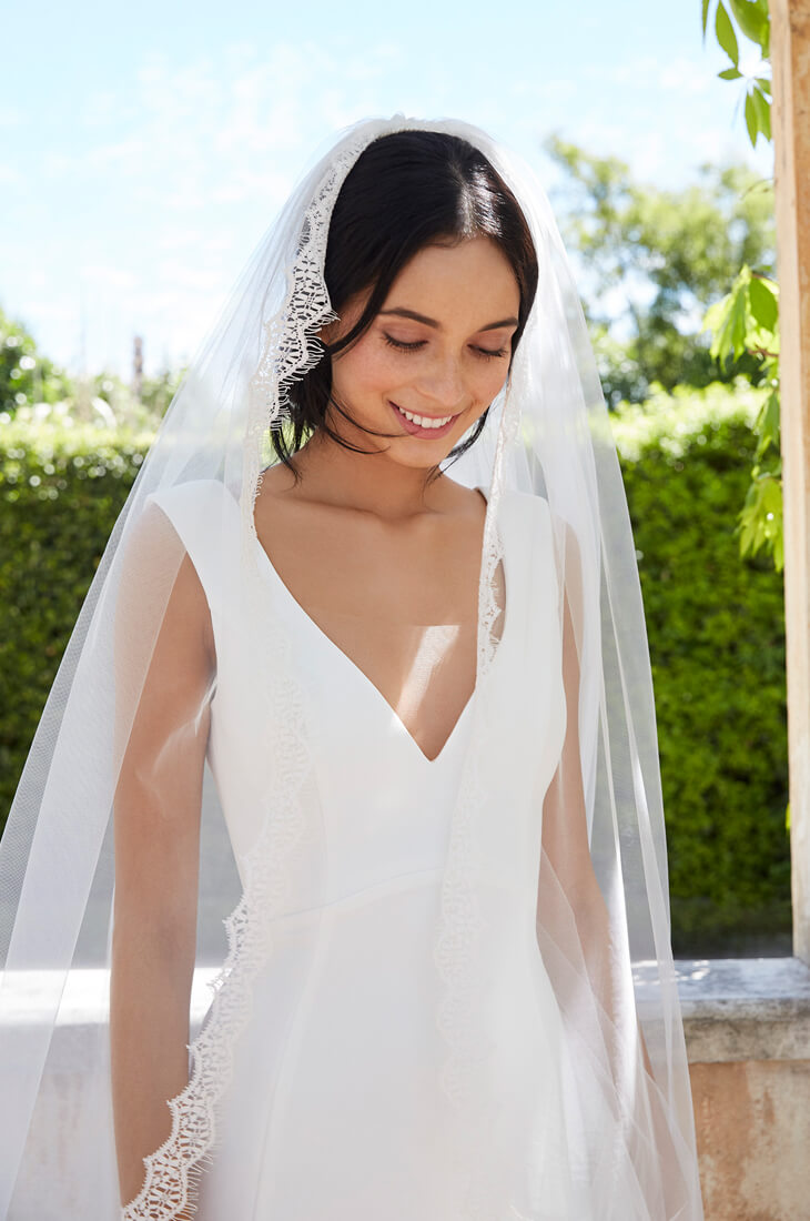 Minimalist wedding dress with lace trimmed veil.