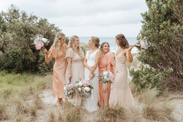 Bride and bridesmaids in pastel, on the beach.