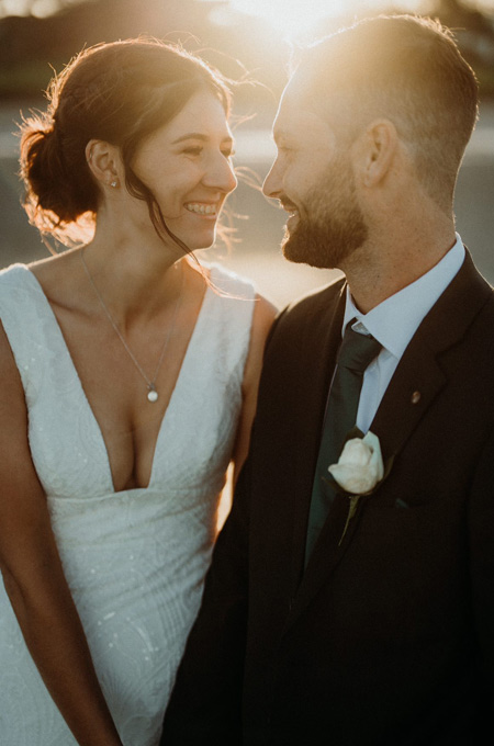 Bride and groom, close up, smiling at each other.