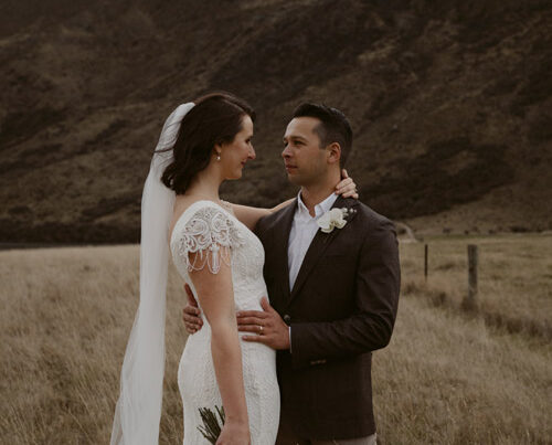 Bride and groom, vintage styled, in front of dark hills.