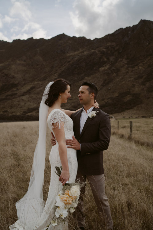 Bride and groom, vintage styled, in front of dark hills.
