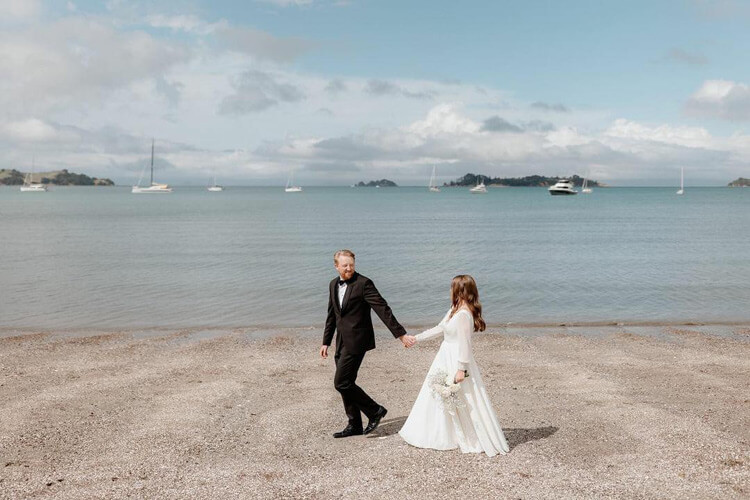 Bride and groom walking along the seashore.