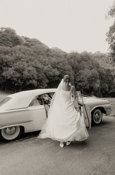 Real bride in front of wedding car, vintage styled.