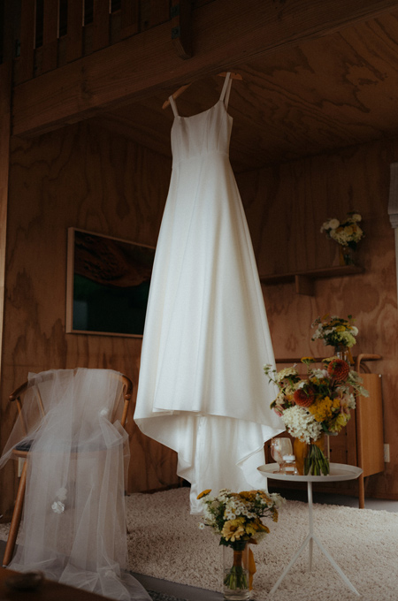 Classic wedding dress hanging on wooden rafters.