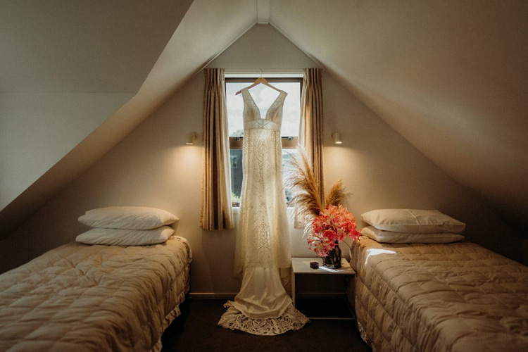 Lace wedding dress, back-lit, hanging in a window.