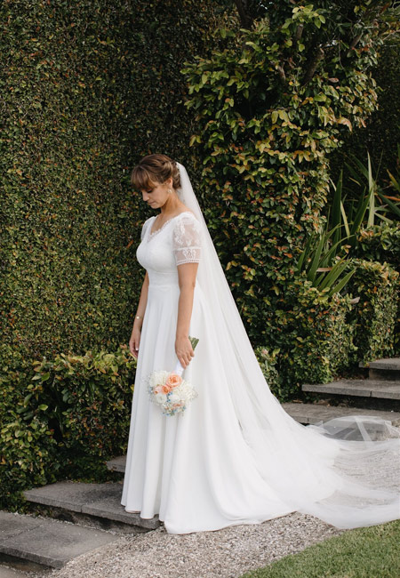Real bride wearing a classic lace and crepe wedding dress.
