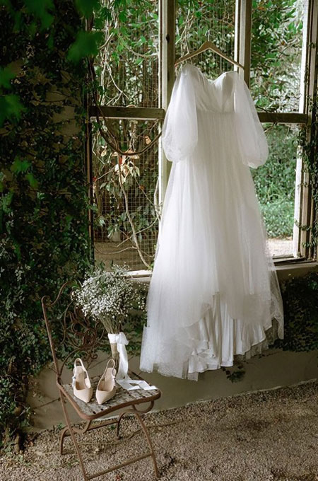 Tulle wedding dress, hanging in a leafy conservatory.