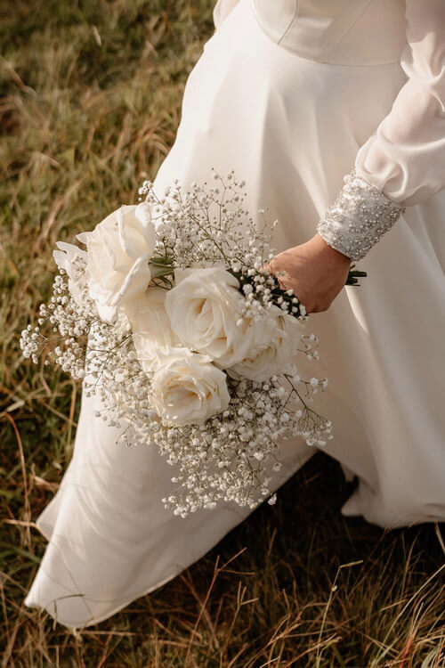 Wedding dress detail, with floral bouquet.