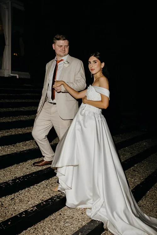 Bride and groom posing on stairs at night.