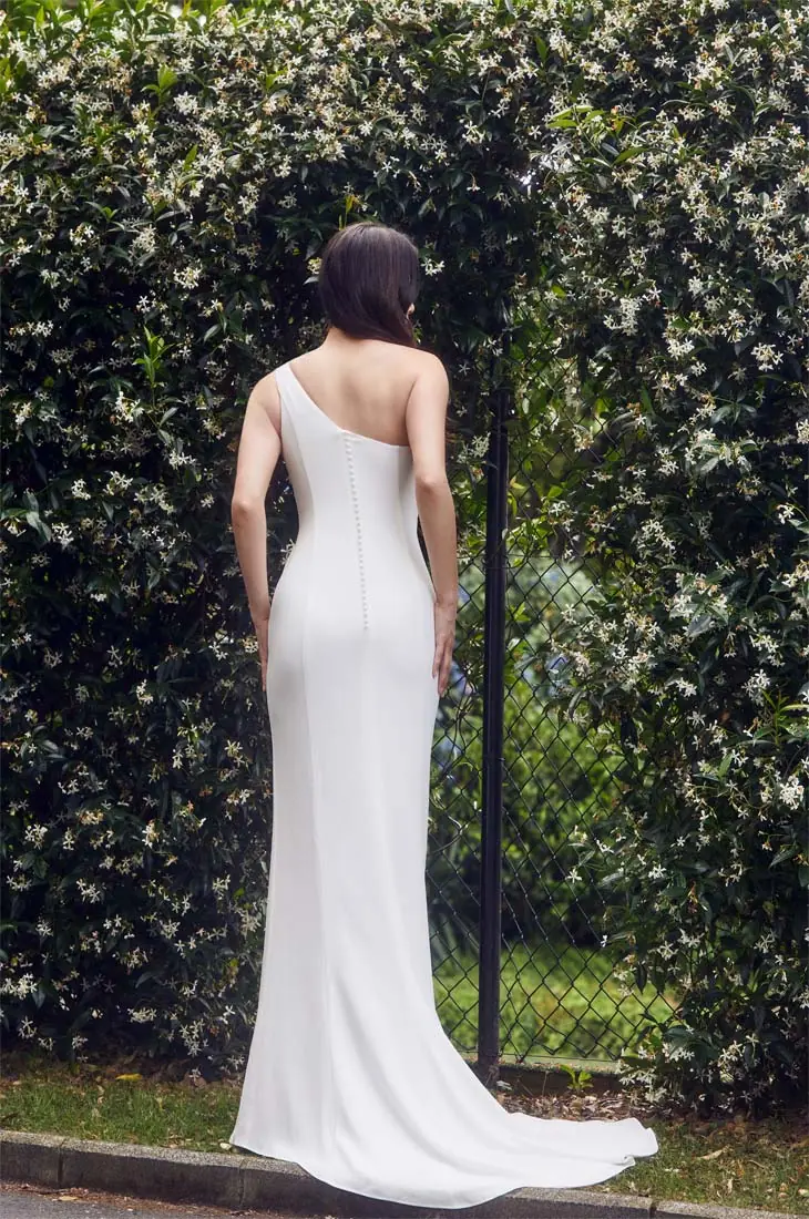Back view of an elegant one-shoulder crepe wedding dress with button detail, designed and fitted in Auckland, New Zealand.